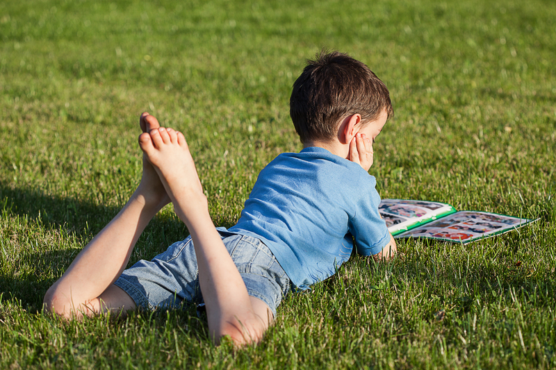 boy in grass reading a book